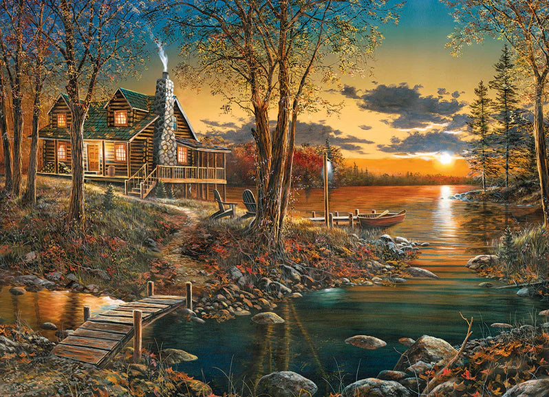 Casse-tête Cobble Hill 1000 pièces – Le confort de la maison – Illustration de Jim Hansel montrant une cabane en rondins au bord d’un lac, entourée de feuillage d’automne et éclairée par un coucher de soleil paisible.